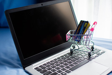 shopping cart and credit card on computer, shopping online concept. subject is blurred and low key.