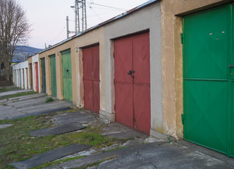 Row of weathered color old metal garage block doors, diagonal view