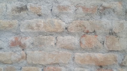 A background of a weathered old exterior brick wall in the sunshine.
