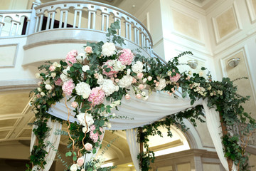 Wedding chuppah decorated with fresh flowers indoor banquet hall of wedding ceremony. Luxury wedding florist decoration artwork