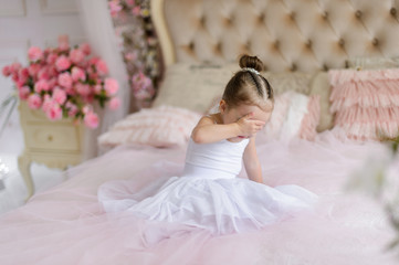 Obraz na płótnie Canvas Beautiful small girl in white dress posing indoor.