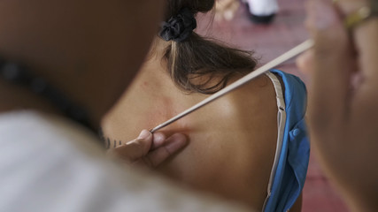 Master makes traditional Yantra tattoo on magic tattoo Sak Yant holiday. Thailand.