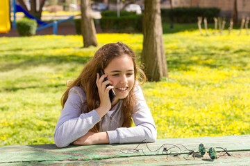 Pretty teenager girl with mobile cellpfone smartphone at the summer park