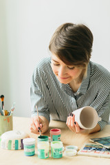the pottery girl holds in hands a mug to paint the ornament