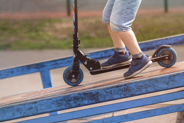 Little boy rides on scooter on ramp and springboard. Concept extreme sport
