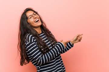 Young intellectual indian woman excited pointing with forefingers away.