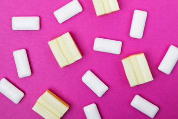 Chewing gum of white and yellow color on a bright pink background. Stylish photo, minimalism, design, flat lay, top view.