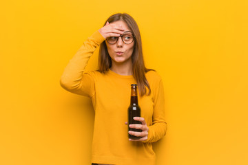 Young pretty caucasian woman worried and overwhelmed. She is holding a beer.