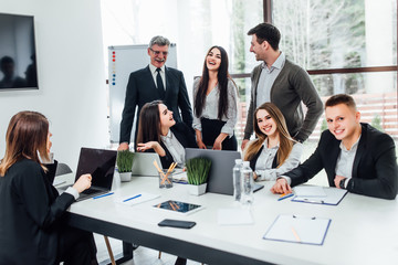 Group of  seven young modern people in smart casual wear discussing something while working in the...
