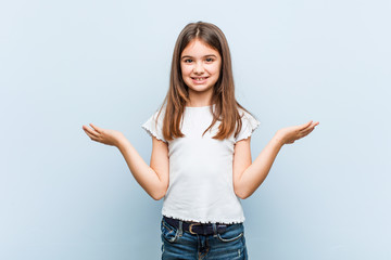 Cute girl makes scale with arms, feels happy and confident.