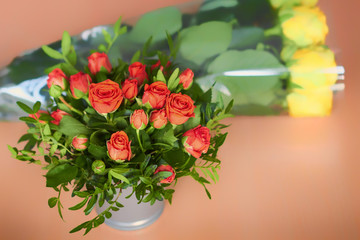 Roses in a metal bucket on the background of a large bouquet. Beautiful flowers in the sunlight. Small red roses on the table.