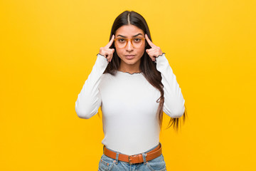 Young pretty arab woman against a yellow background focused on a task, keeping forefingers pointing...