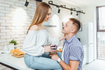 Fototapeta premium Romantic young couple drinking coffee together in the kitchen,having a great time together.