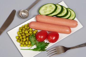 Snack with sausages, cucumber, tomatos and canned peas on gray background, isolated