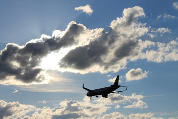Flying plane in the blue sky with clouds