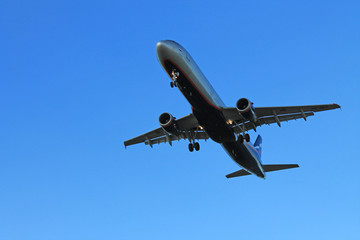 Flying plane in the blue sky with clouds