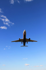 Flying plane in the blue sky with clouds