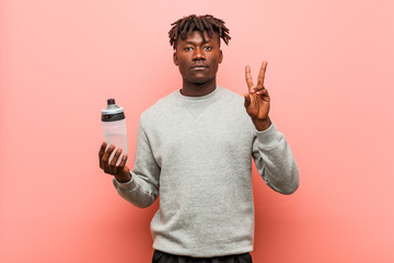 Young fitness black man holding a water bottle showing number two with fingers.