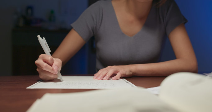 Woman write on the paper at home in the evening - Powered by Adobe