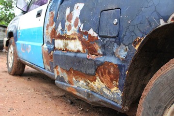 The side of the blue car is broken and has brown rust