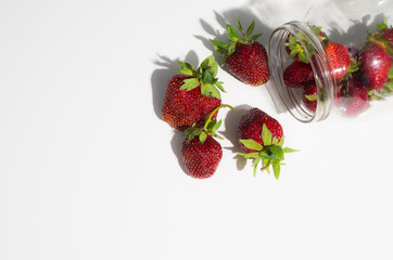 strawberry dropped from the jar on the white table