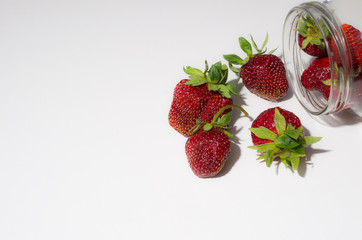 strawberry dropped from the jar on the white table