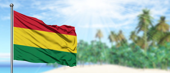 Waving Bolivia flag in the sunny blue sky with summer beach background. Vacation theme, holiday concept.