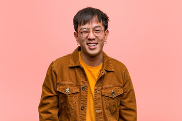 Young chinese man wearing a jacket winking, funny, friendly and carefree gesture