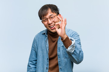 Young chinese man cheerful and confident doing ok gesture