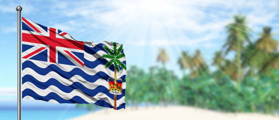 Waving British Indian Ocean Territory flag in the sunny blue sky with summer beach background. Vacation theme, holiday concept.