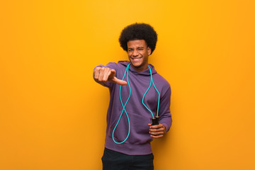 Young african american sport man holding a jump rope cheerful and smiling pointing to front - Powered by Adobe