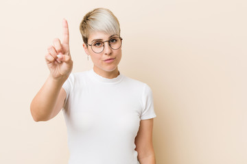 Young authentic natural woman wearing a white shirt showing number one with finger.