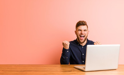 Young man working with his laptop cheering carefree and excited. Victory concept.
