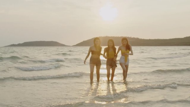 Group of Asian young women running on beach, friends happy relax having fun playing on beach near sea when sunset in evening. Lifestyle friends travel holiday vacation summer concept. Slow motion shot