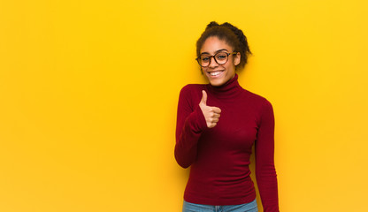 Young black african american girl with blue eyes smiling and raising thumb up