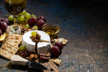 Camembert cheese, snacks and a glass of white wine, closeup