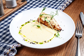 Close up view on served chicken fillet with polenta and corn sauce on wooden background. Modern cuisine. Copy space. Picture for recipe or menu