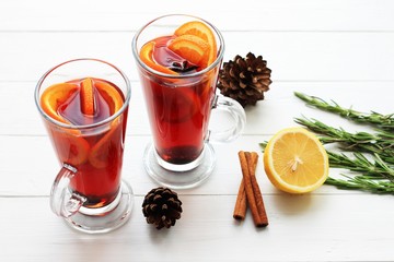 Two glasses of hot red mulled wine or gluhwein with orange, cinnamon sticks on light background. Spicy warm beverage. Seasonal mulled drink.