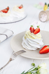 Close up view on tasty Pavlova cake dessert with strawberry on white wooden background. Delicious traditional Australian dessert from meringue and cream. Picture for recipe. selective focus.Copy space