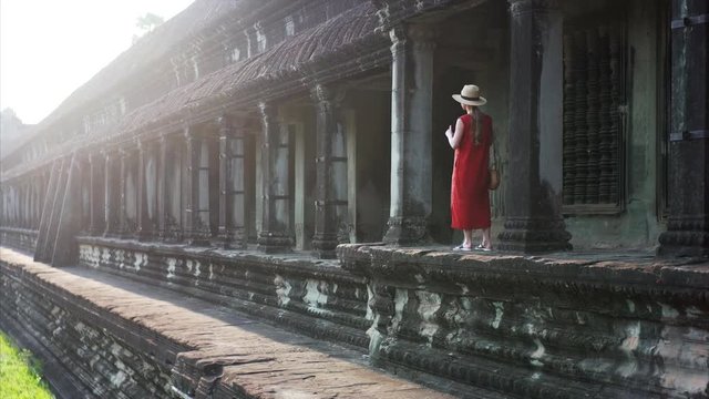 Sliding view of young woman taking photo of beautiful gallery of of Angkor Wat temple built in 12th century in Cambodia and dedicated to Vishnu. Cambodia
