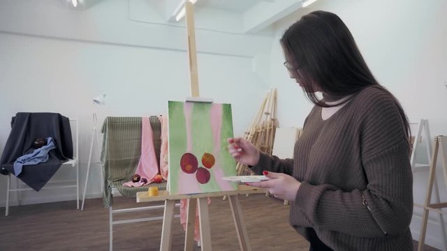 Young girl with a brush draws a still life