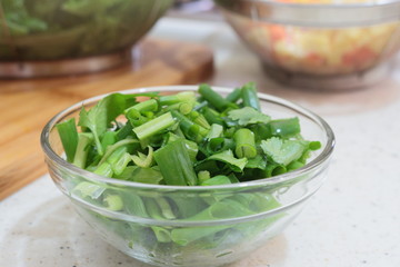 Glass bowl of cilantro and chives sliced. Ingredients to make a healthy dish 