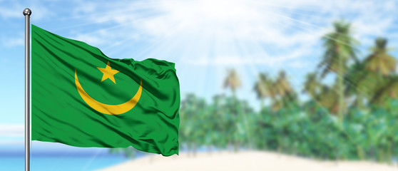 Waving Mauritania flag in the sunny blue sky with summer beach background. Vacation theme, holiday concept.