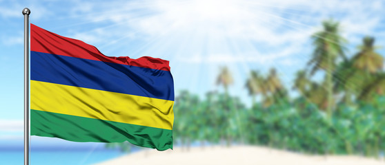 Waving Mauritius flag in the sunny blue sky with summer beach background. Vacation theme, holiday concept.