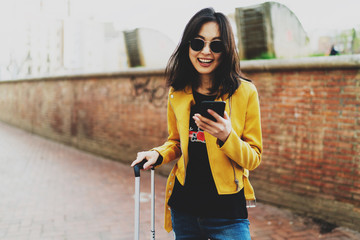 Charming asian tourist female with long dark hair wearing modern sunglasses smiling at the camera...
