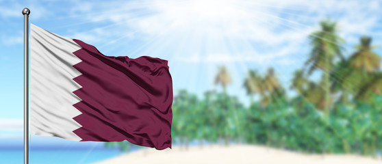 Waving Qatar flag in the sunny blue sky with summer beach background. Vacation theme, holiday concept.