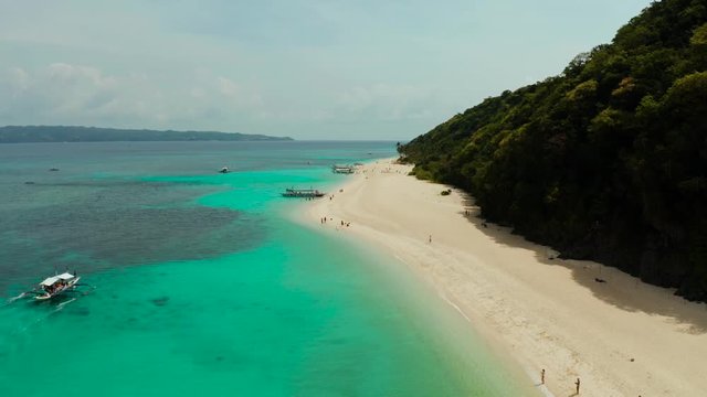 Tropical white sand beach, near the blue lagoon and corall reef from above, Boracay, Philippines. Sandy beach with tourists. Summer and travel vacation concept.