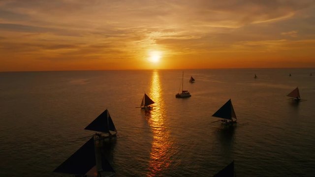 Sunset over the sea surface with sailing boats from above Boracay, Philippines. Reflected sun on a water surface. Sunset over ocean. Seascape, Summer and travel vacation concept