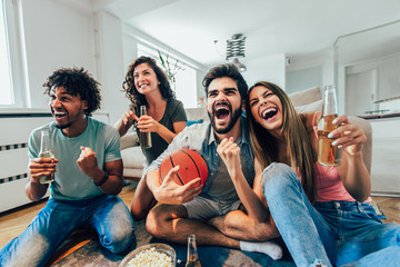 Happy friends or basketball fans watching basketball game on tv and celebrating victory at home.Friendship, sports and entertainment concept. - Powered by Adobe