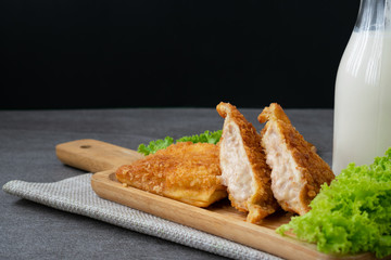 Deep fried sandwich stuffed tuna in wooden dish on table.